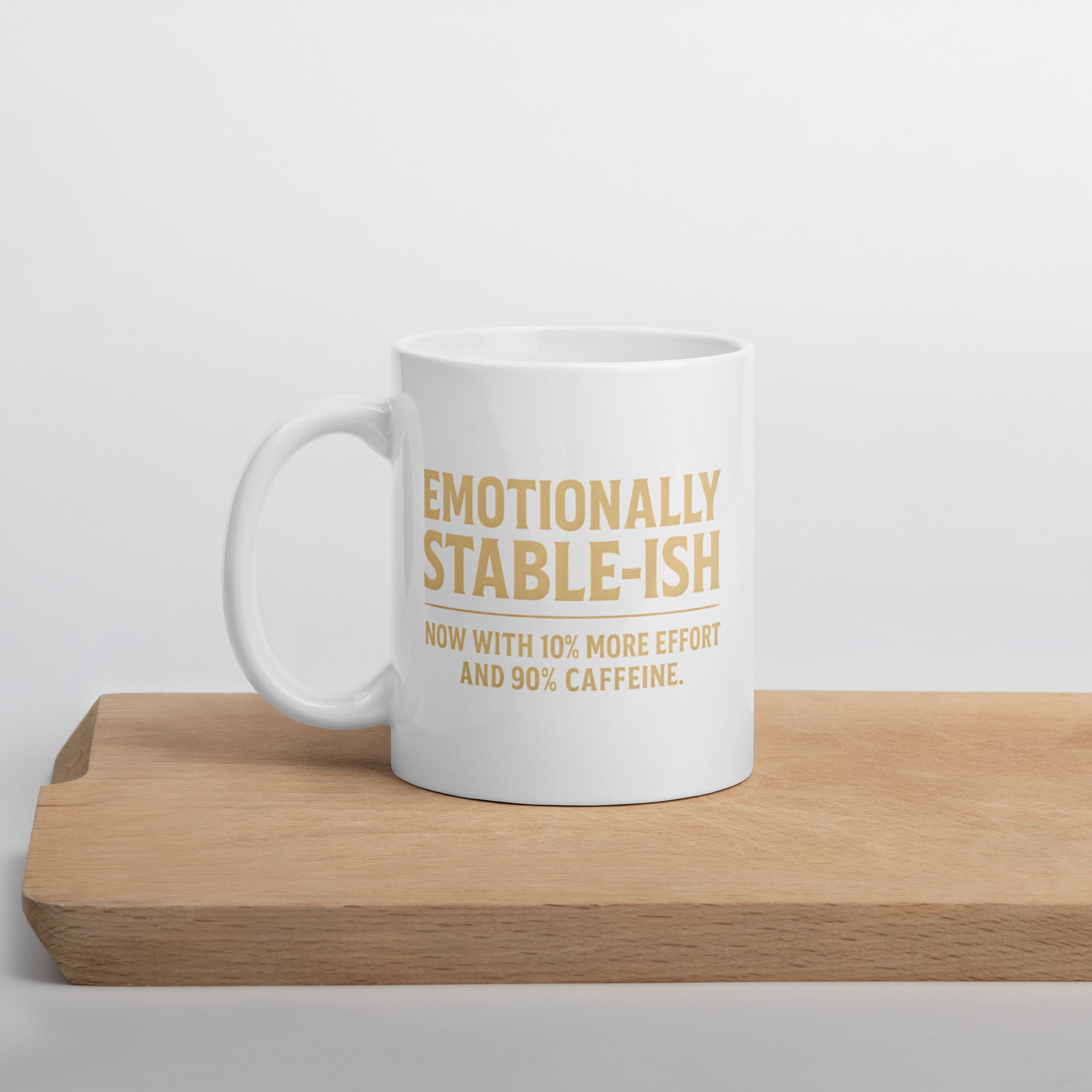 White mug with beige text that says, “Emotionally stable-ish. Now with 10% more effort and 90% caffeine.