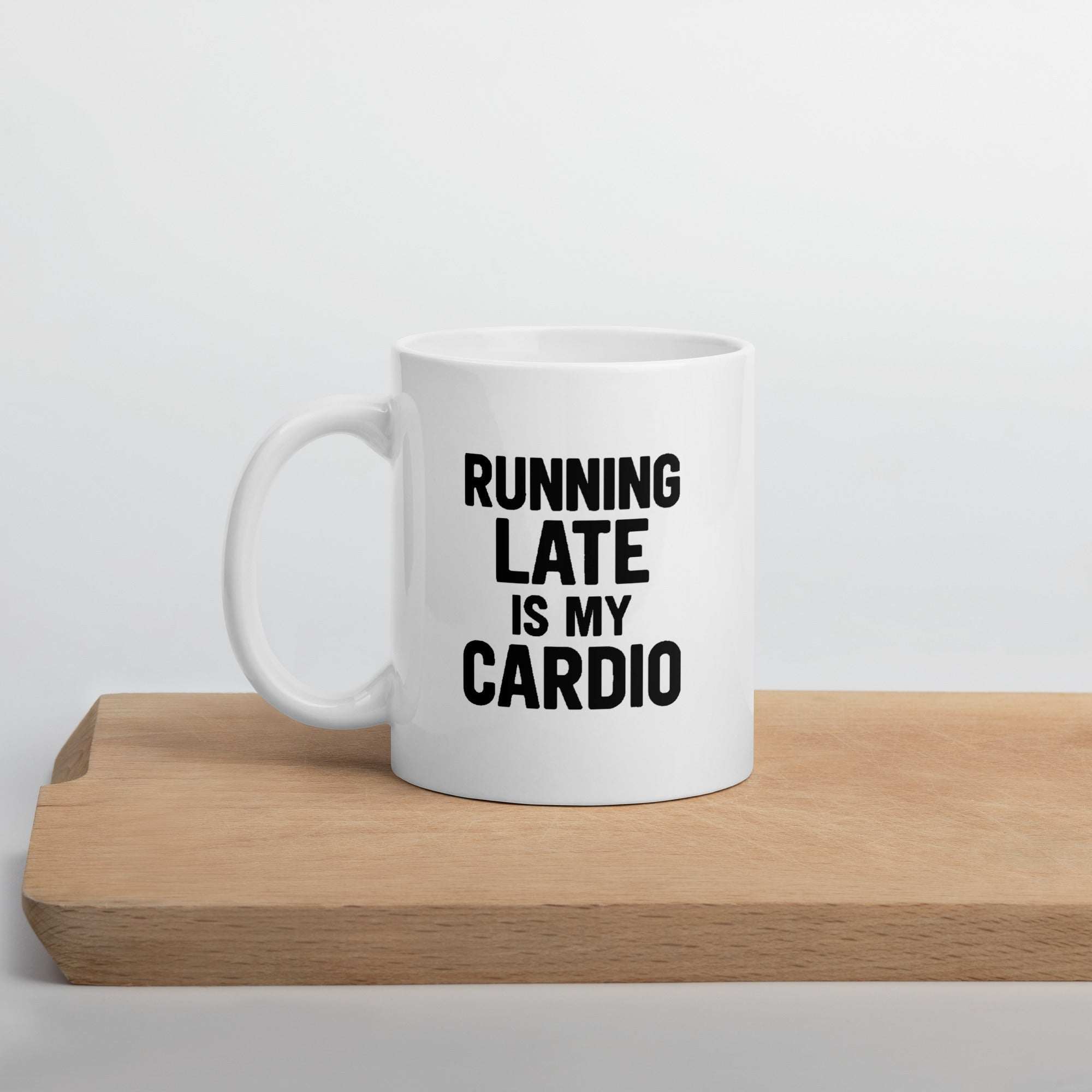 White mug with bold black text that says, “Running late is my cardio.”