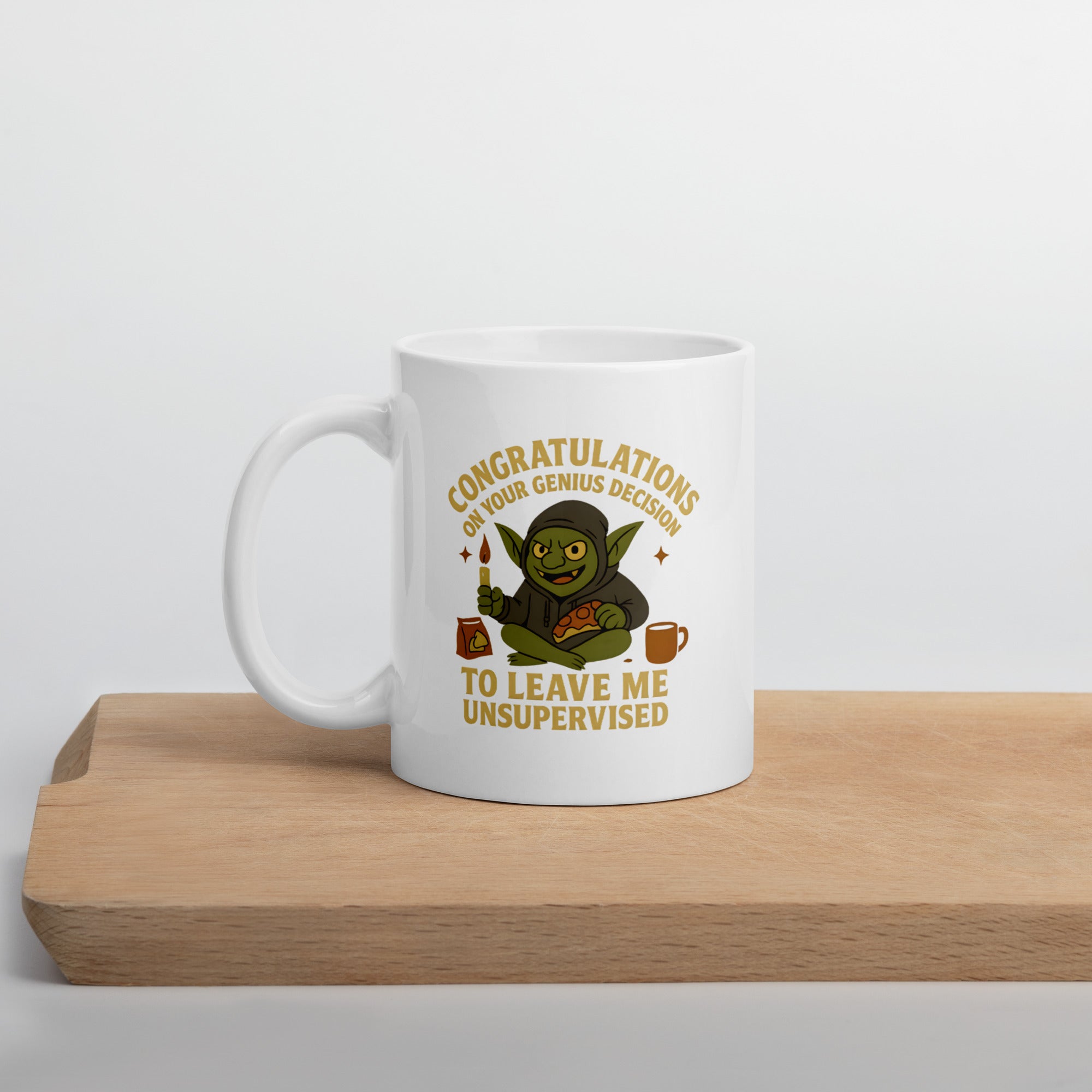 White mug with a cartoon goblin holding paint and a slice of pizza, surrounded by text that says, “Congratulations on your genius decision to leave me unsupervised.”