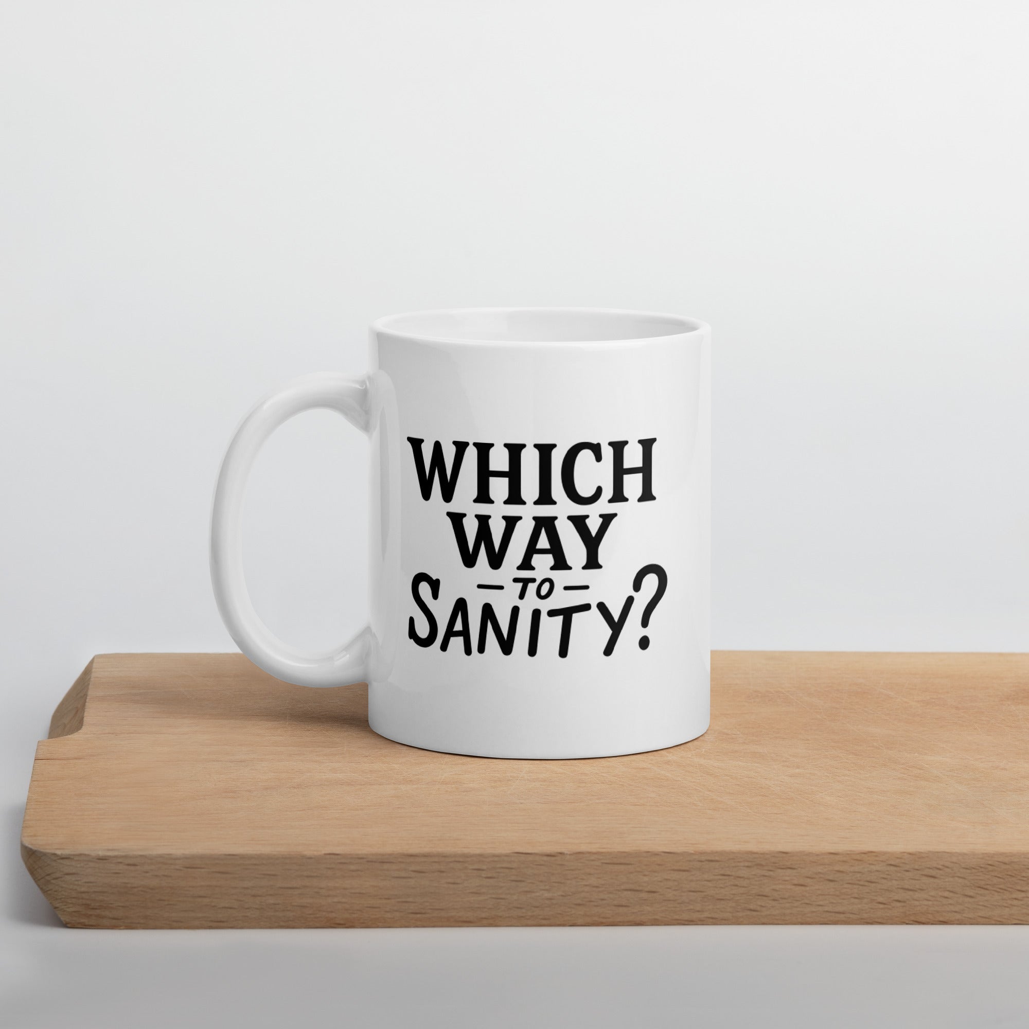 White mug with bold black text that reads, “Which way to sanity?”
