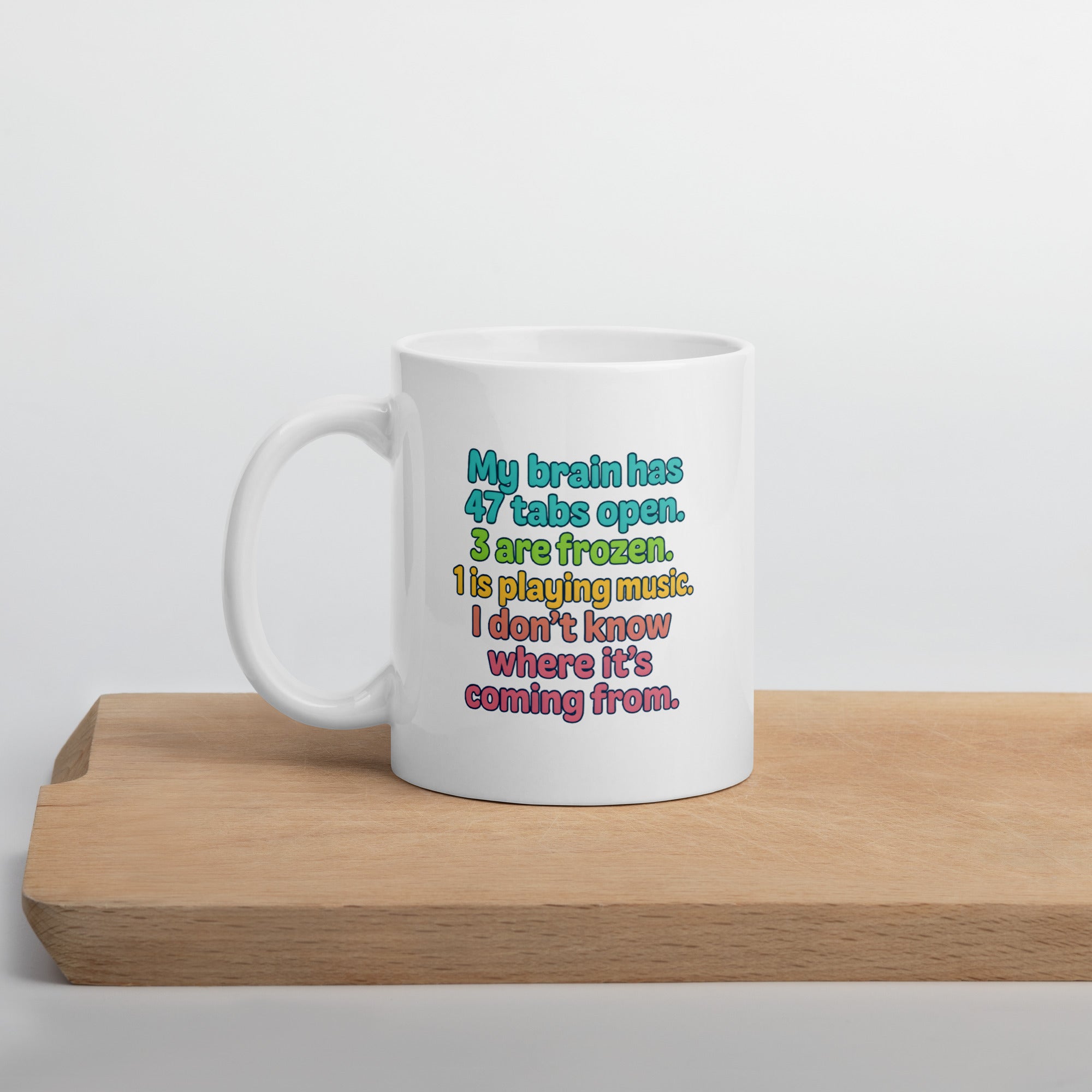 White mug with colorful text that says, “My brain has 47 tabs open. 4 are frozen. 1 is playing music. I don’t know where it’s coming from.”