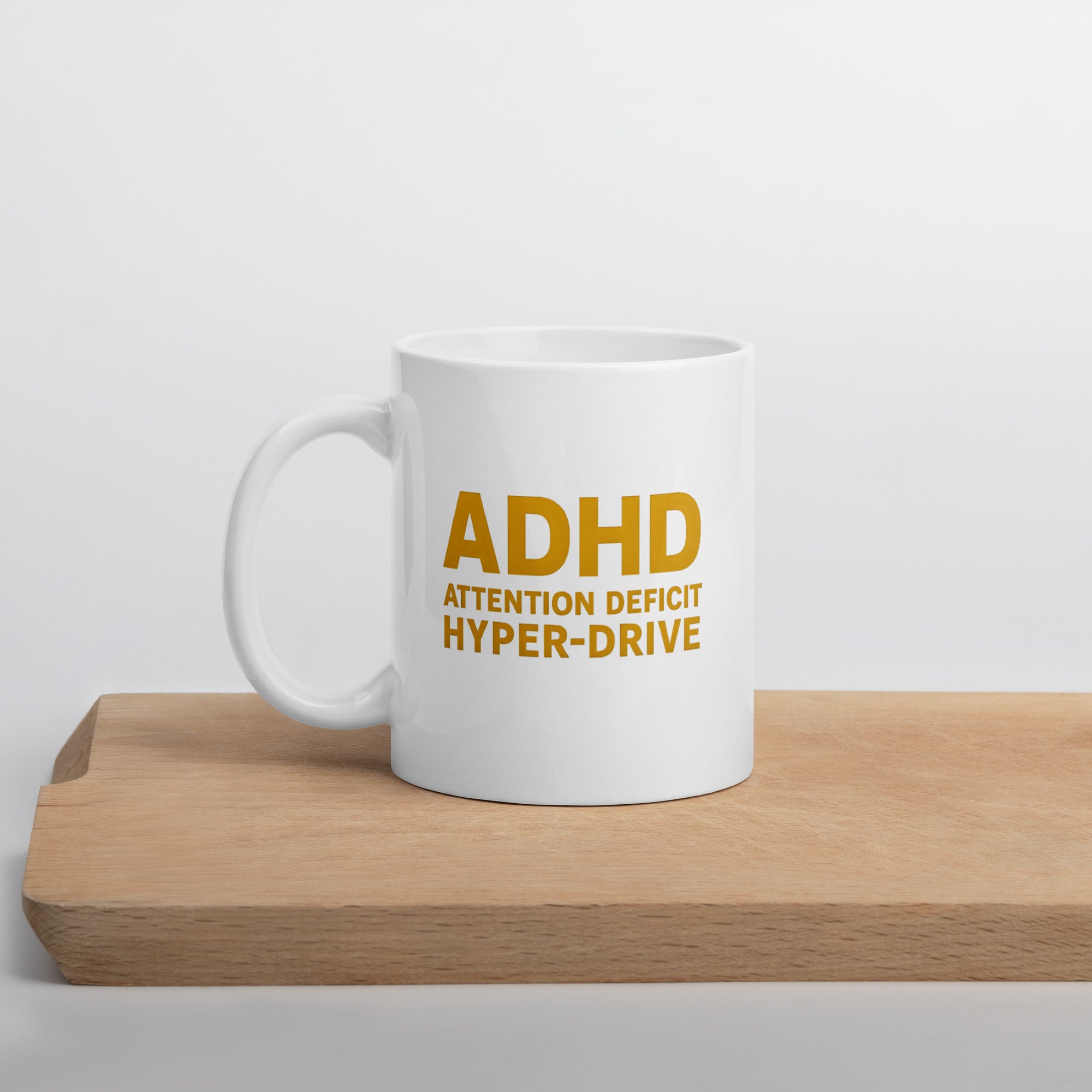 White mug with bold yellow text that reads, “ADHD Attention Deficit Hyper-Drive.”